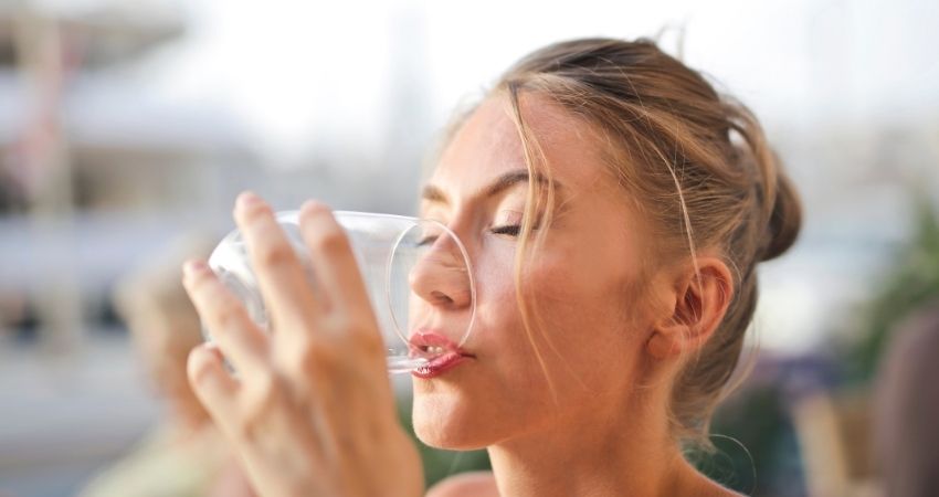 Una mujer tomando más agua para estar saludable